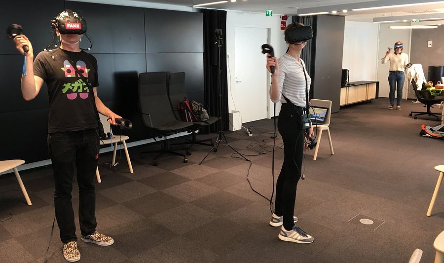 Photo of three people collaborating in virtual reality wearing brain measurement caps
