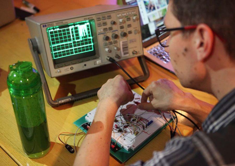 Person measuring an electronic circuit with an oscilloscope