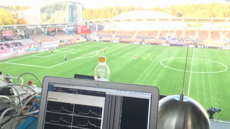 Photo of screen showing EEG data in foreground and football field in background